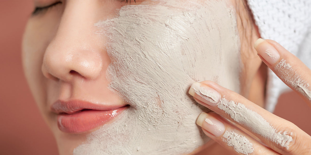 Smiling woman with bentonite clay mask on half of her face