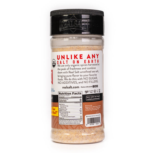 Clear shaker of Real Salt brand organic seasoned salt on a white background, showcasing the nutritional information and company branding.