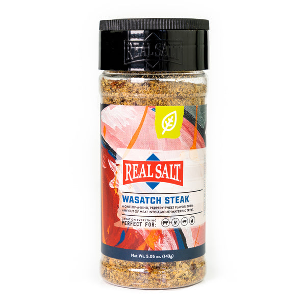 A clear jar displays the coarse texture of Real Salt's Wasatch Steak seasoning, promising a peppery-sweet flavor.