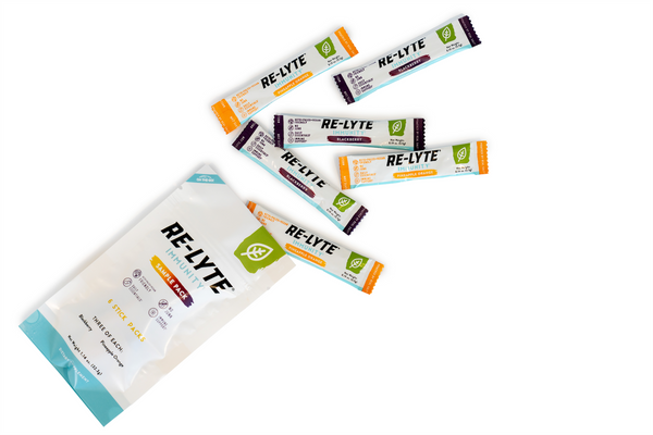 Six single-serving stick packs of Re-Lyte Immunity electrolyte powder in Blackberry and Pineapple Orange flavors spill out of a sample pack.