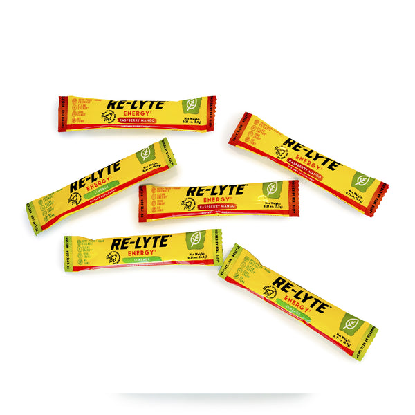 Several single-serving pouches of Re-Lyte Energy supplement in Raspberry Mango and Limeade flavors lay scattered on a white surface.