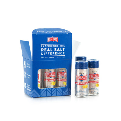Open box displays four RealSalt Ancient Fine Sea Salt shakers against a white background. 
