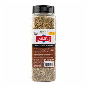 Clear plastic jar filled with Redmond Real Salt brand Organic Garlic Pepper seasoning.