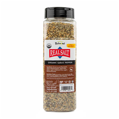 Clear plastic jar filled with Redmond Real Salt brand Organic Garlic Pepper seasoning.