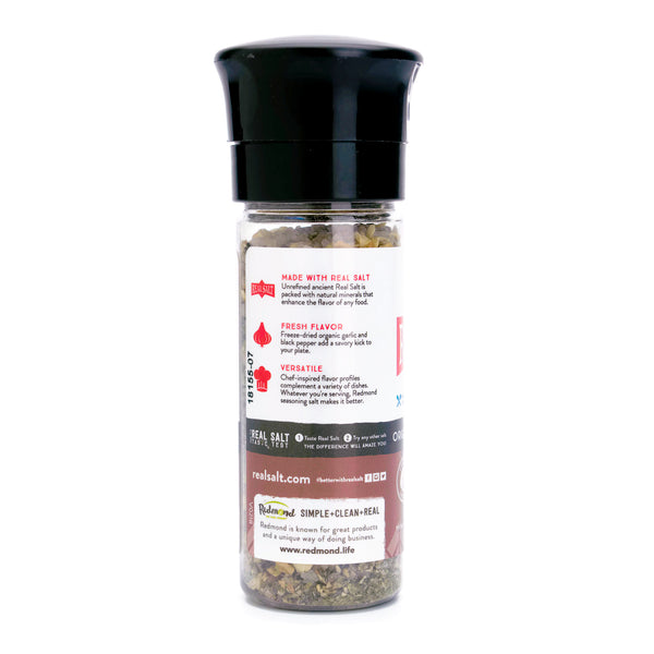 A grinder filled with Redmond Real Salt seasoned with garlic and black pepper sits on a white background.