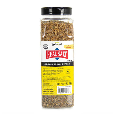 A clear jar displays Redmond Real Salt's Organic Lemon Pepper seasoning, featuring a blend of ancient sea salt, lemon peel, black pepper, garlic, onion, and thyme. 
