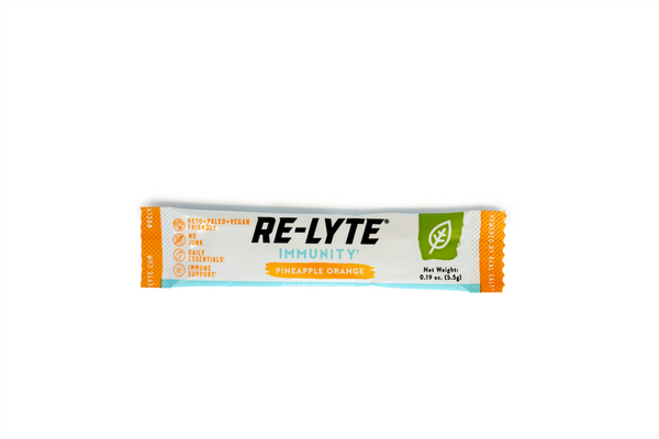 A single-serving packet of Re-Lyte Immunity Pineapple Orange dietary supplement lies horizontally against a white background. 
